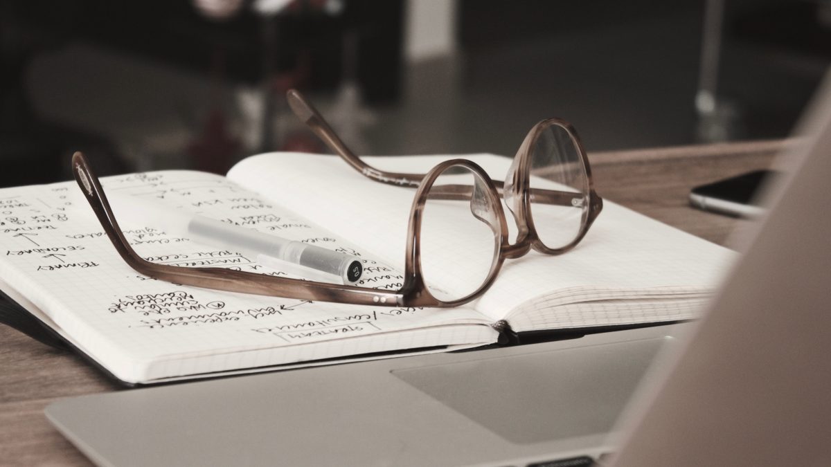 Glasses resting on a book on a desktop