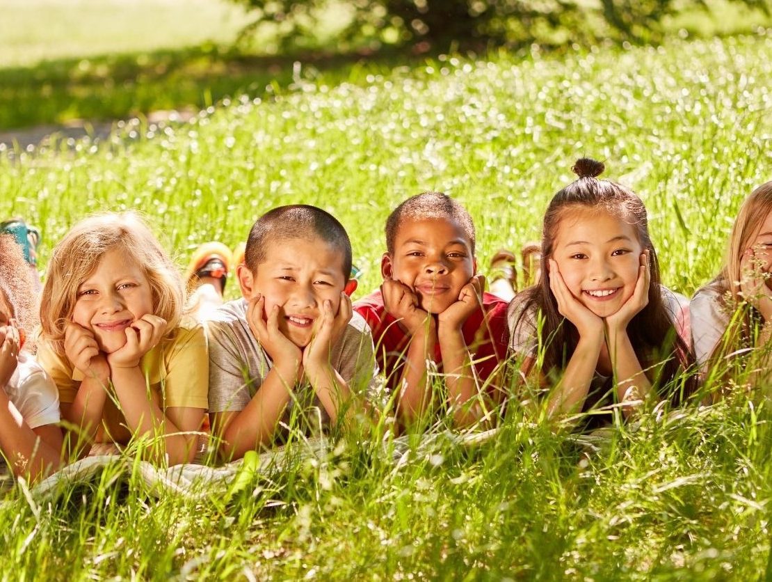 Children in grass cupping their chins