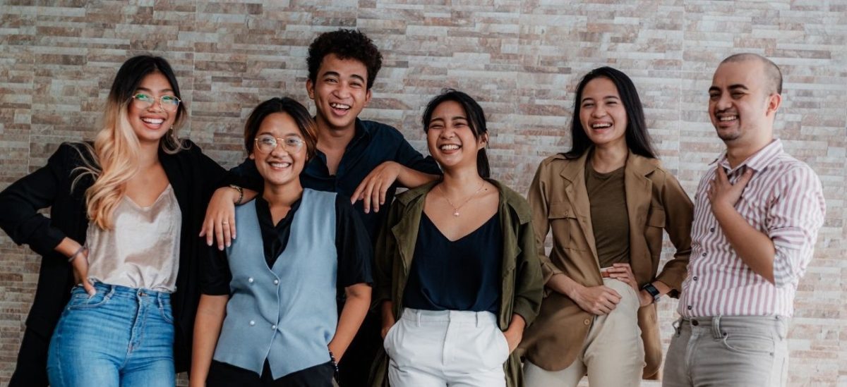 Group of happy young adults in front of brick wall