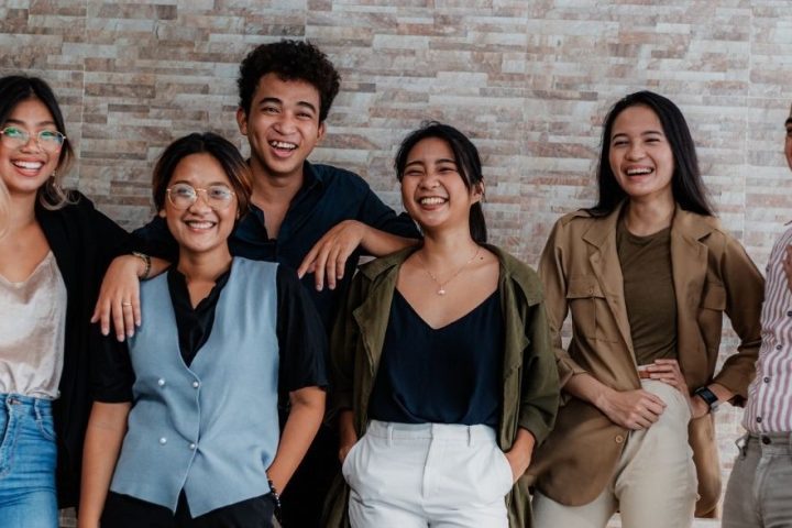 Group of happy young adults in front of brick wall